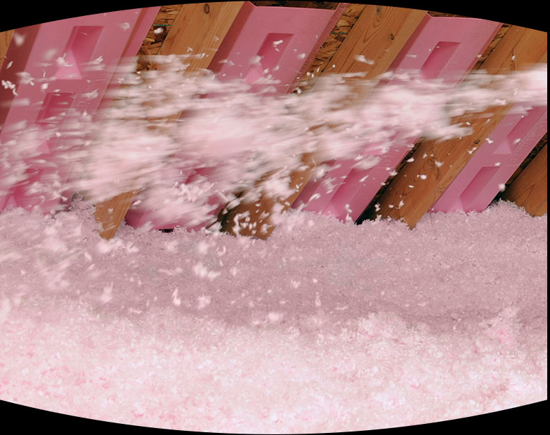 Pink insulation being sprayed into an attic.